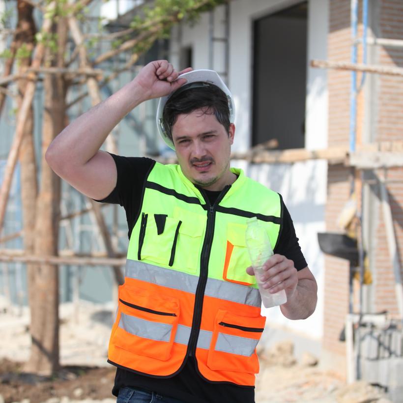 Travailleur du bâtiment bossant sous la chaleur, avec une bouteille d'eau en main