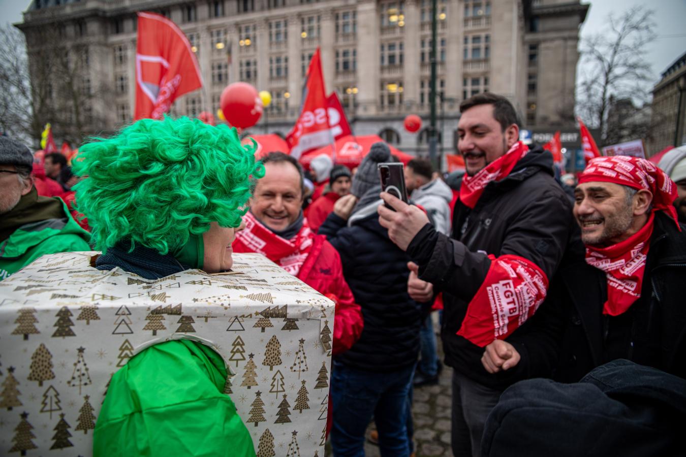Des syndicalistes rouges prennent une verte déguisée en cadeau de Noël.