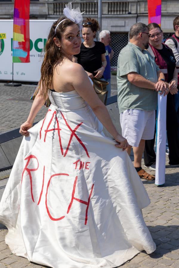 Une femme habillée d'une robe blanche sur laquelle est écrit "Tax the rich"