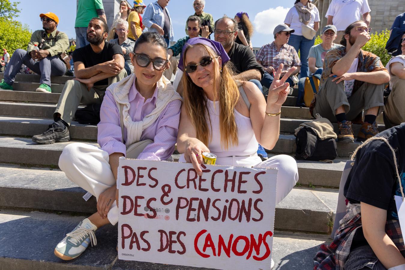 Deux femmes posent avec une affiche "Des crèches et des pensions, pas des canons"