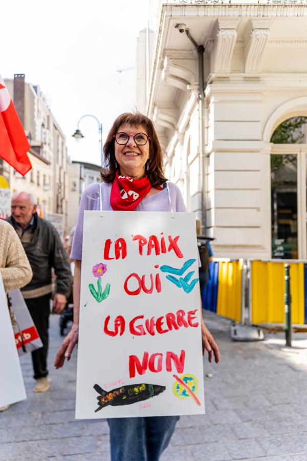 Une femme marche avec une pancarte "La paix, oui. La guerre, non"