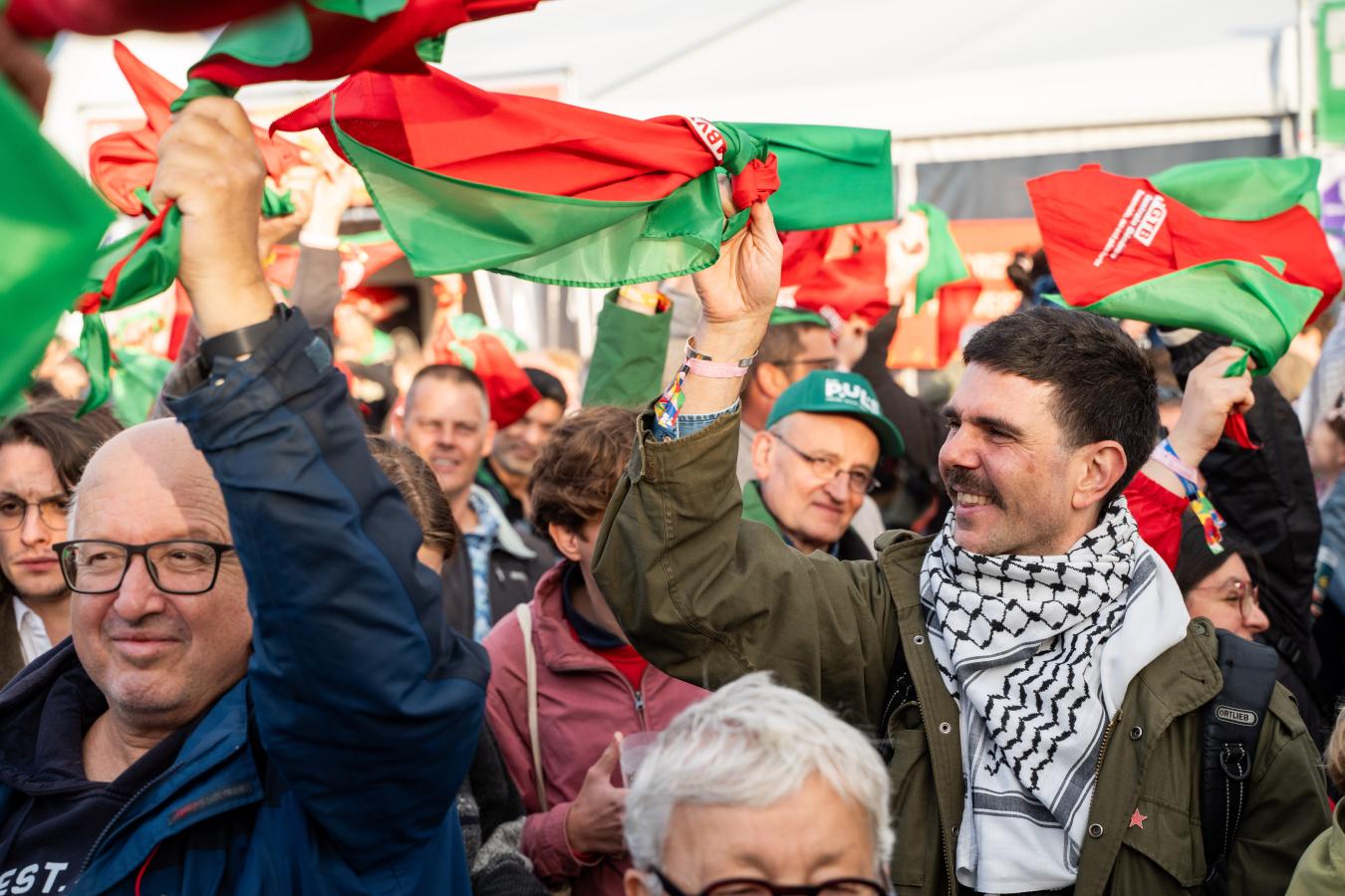 Une foule qui tient et agite de petits drapeaux palestiniens