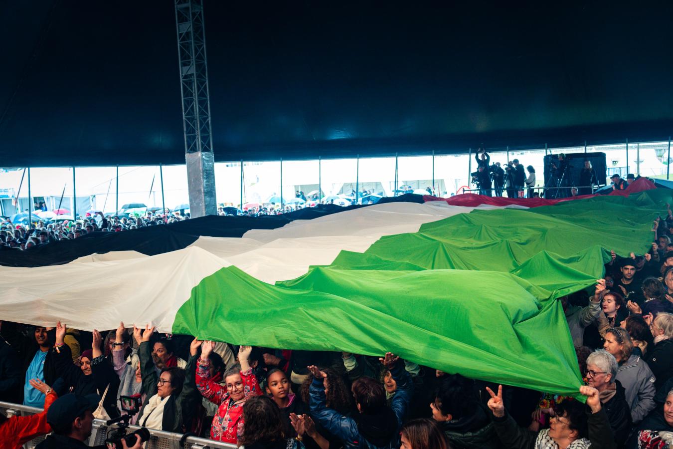 Un grand drapeau palestinien porté par la foule devant la Main Stage de ManiFiesta