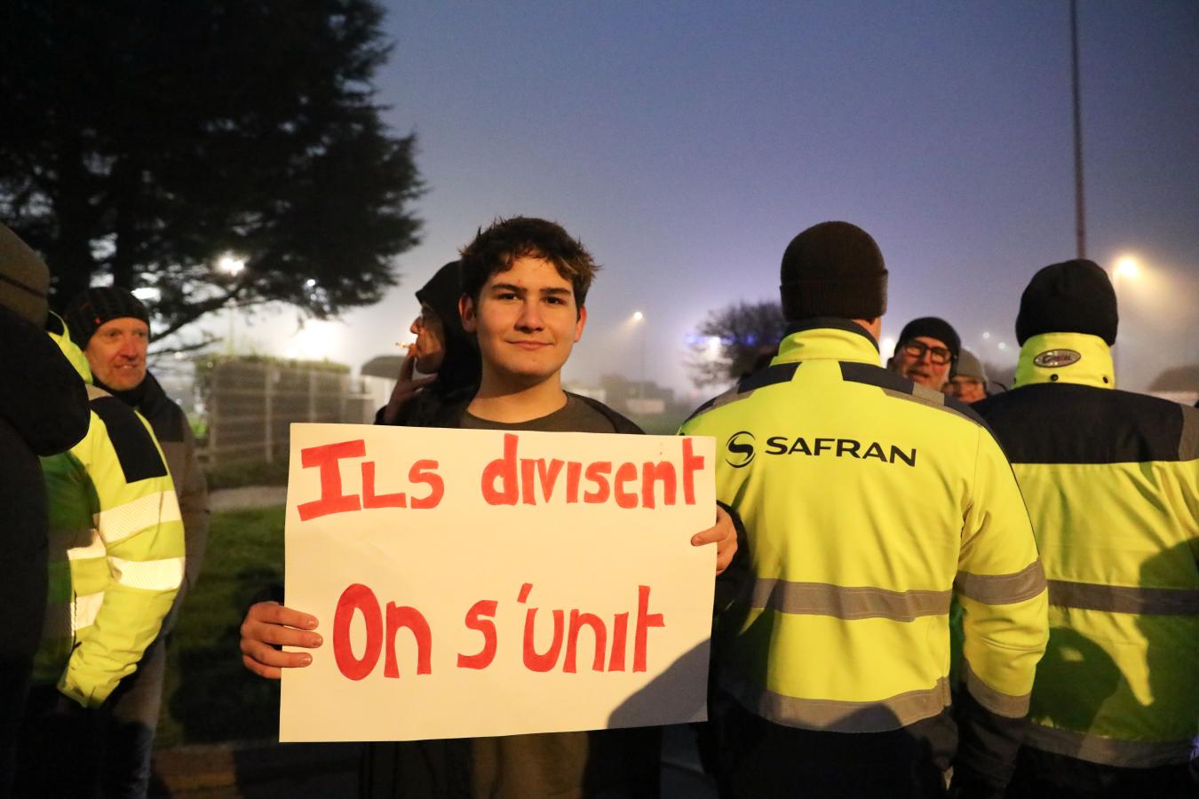 Travailleur avec une pancarte "Ils divisent, on s'unit"