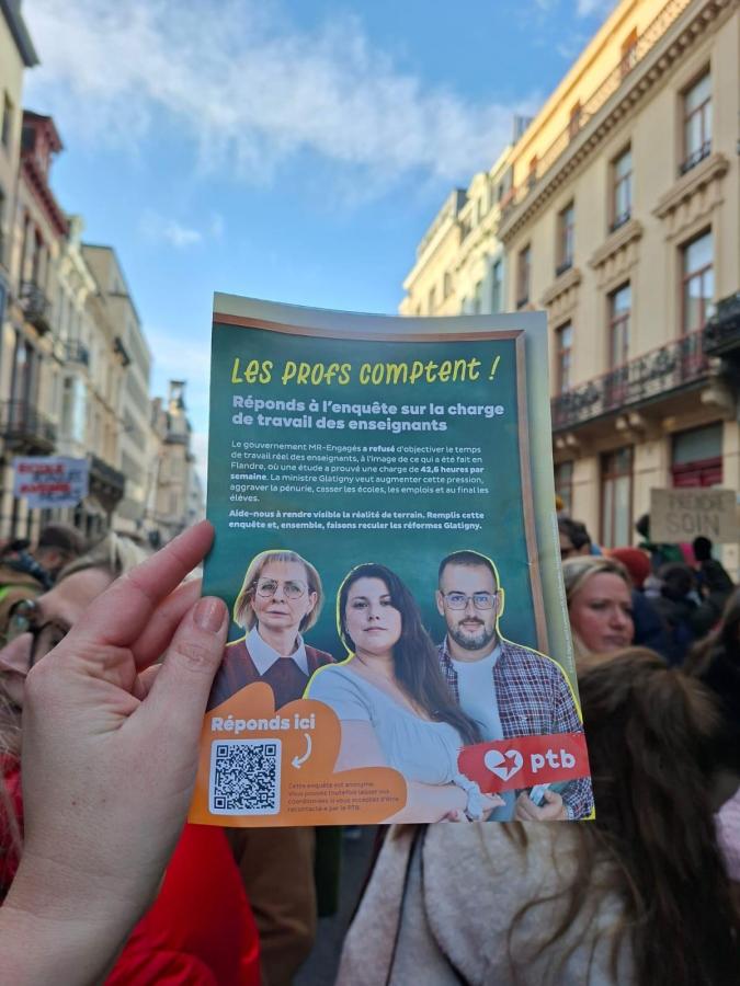Une main tenant le flyer pour l'enquête sur le temps de travail des profs à la manifestation du 25 janvier 2026