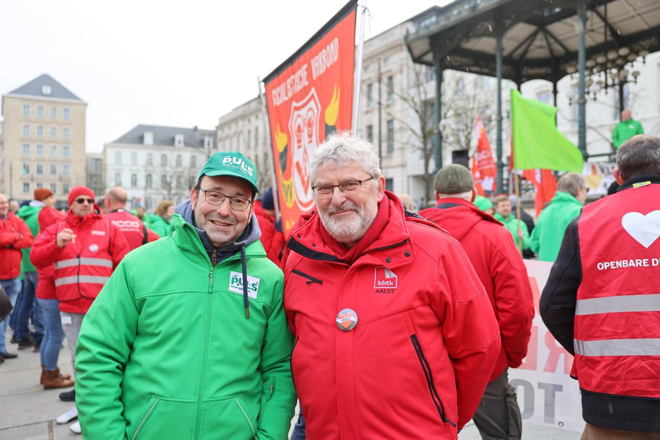 Deux syndicalistes, un rouge et un vert, devant un rassemblement à Gand pour la journée d'actions du 5 février 2026