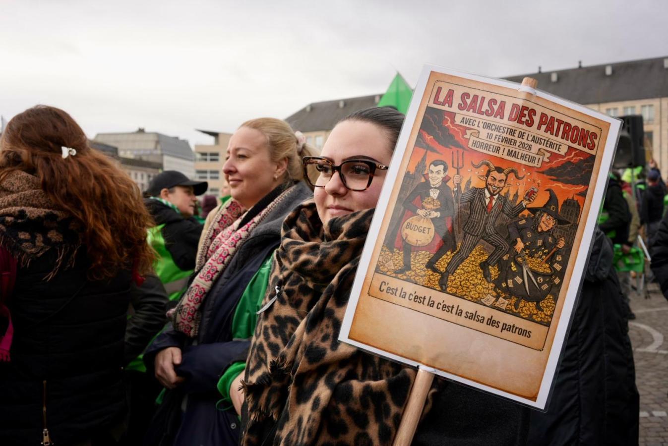 Une jeune femme au milieu de la foule pendant la journée d'actions à Liège. Sur sa pancarte : "La salsa des patrons"
