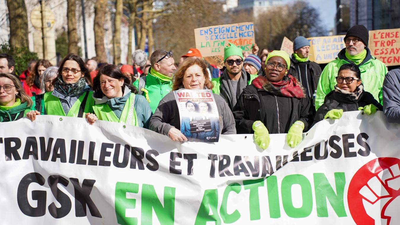 Une femme tient une affiche Wanted devant un bloc vert lors de la manifestation nationale du 12 mars 2026