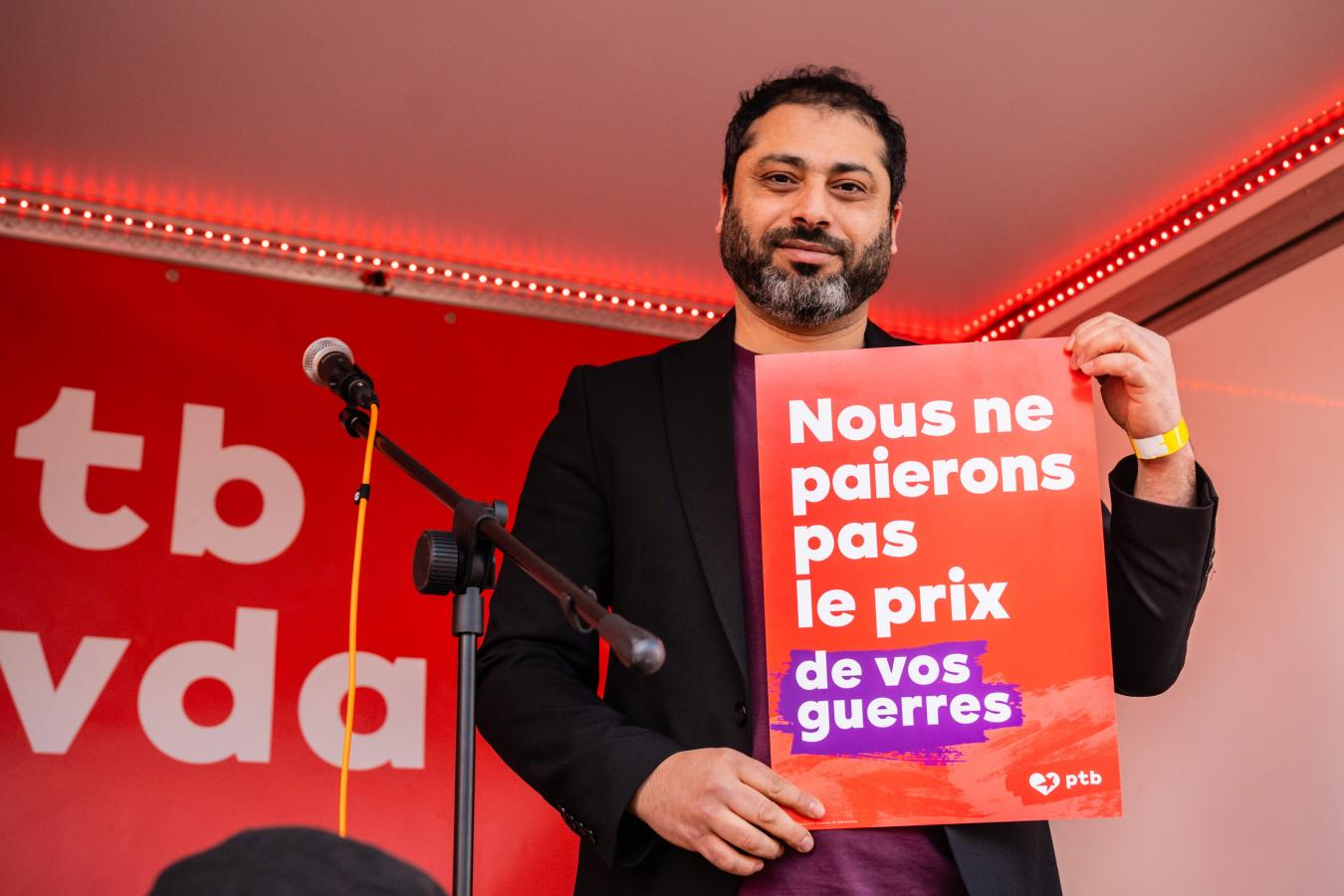 Nabil Boukili tient une pancarte "Nous ne paierons pas le prix de vos guerres"