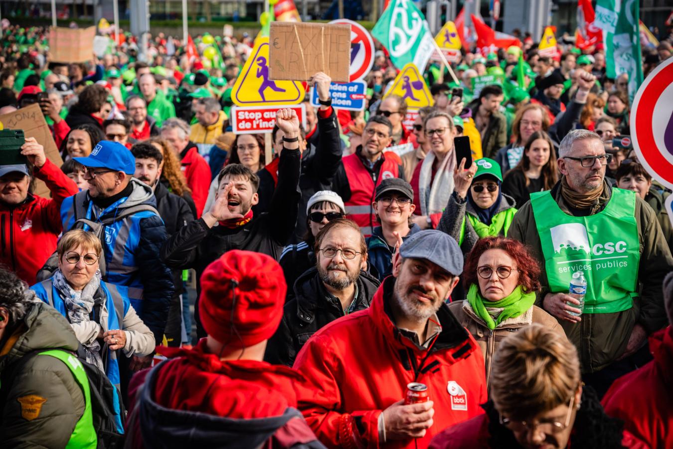Un jeune homme au lieu de la foule tient une pancarte "Tax the rich"