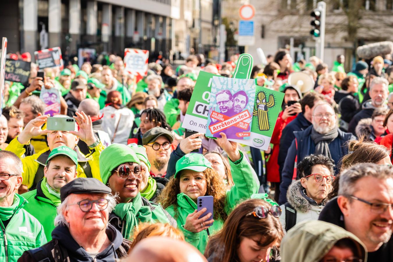 Une femme au milieu de la foule tient une affiche "Arrêtons-les" avec les visages de De Wever et Bouchez