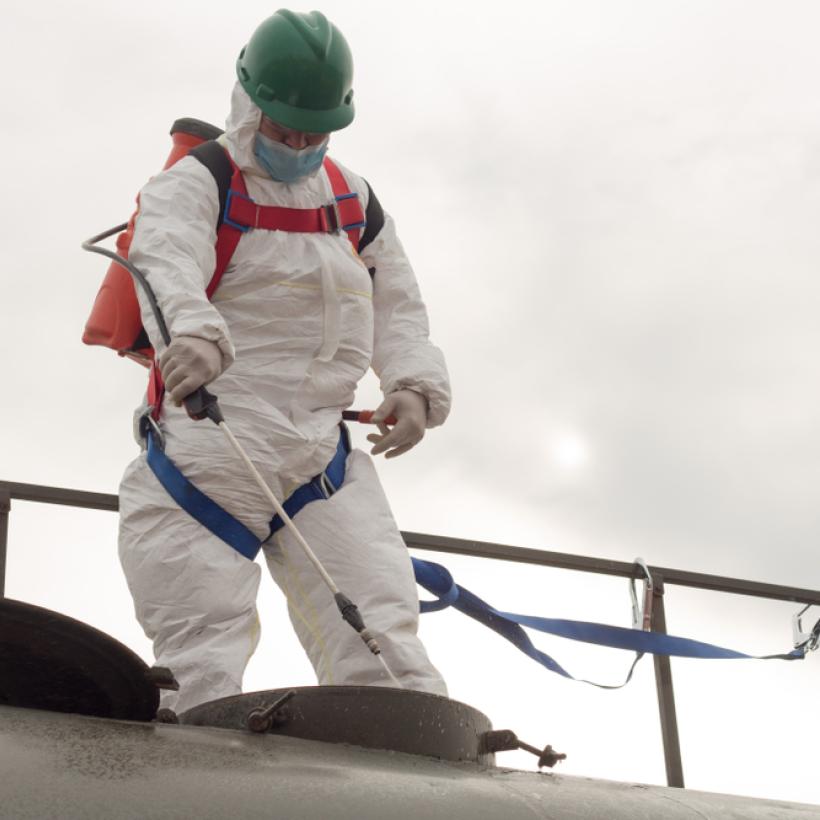 Un homme en combinaison procède à la désinfection d'un réservoir d'eau. (Photo d'ilustration)