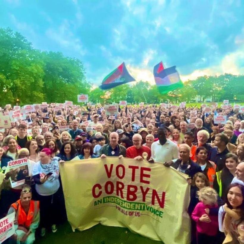 Jeremy Corbyn se tient devant une foule de sympathisants, avec une banderole "Vote Corbyn"