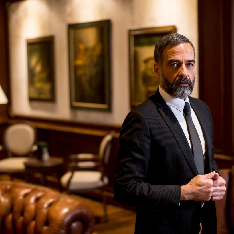 Un homme riche en costume dans un intérieur luxueux.