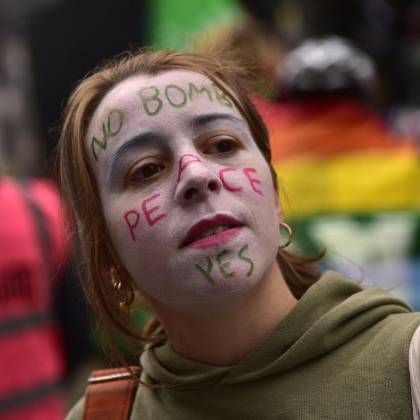 Jonge vrouw op een vredesbetoging, met op haar gezicht geschminkt: “No bombs, peace yes”