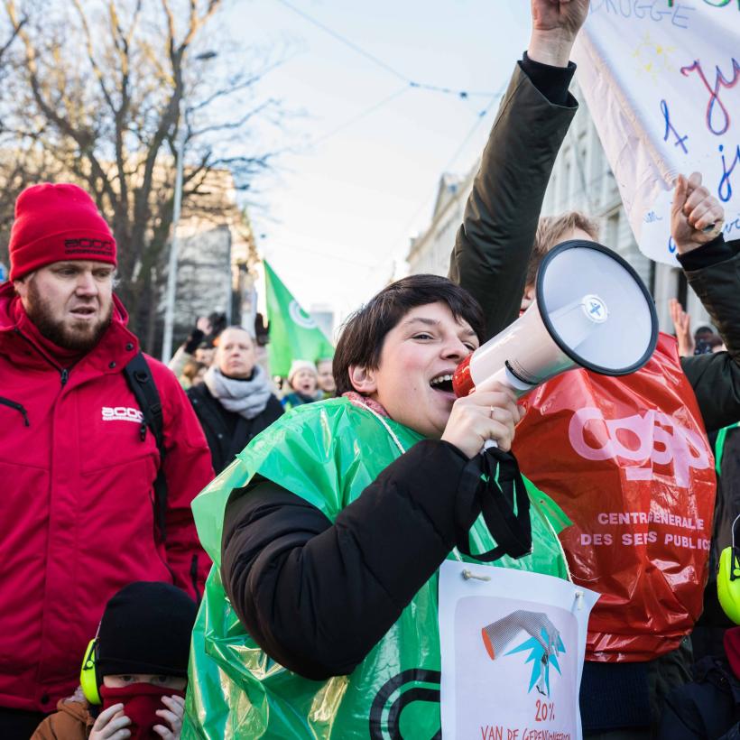 Des personnes manifestant contre le gouvernement Arizona le 13 janvier à Bruxelles. Une jeune fille tient un mégaphone au milieu