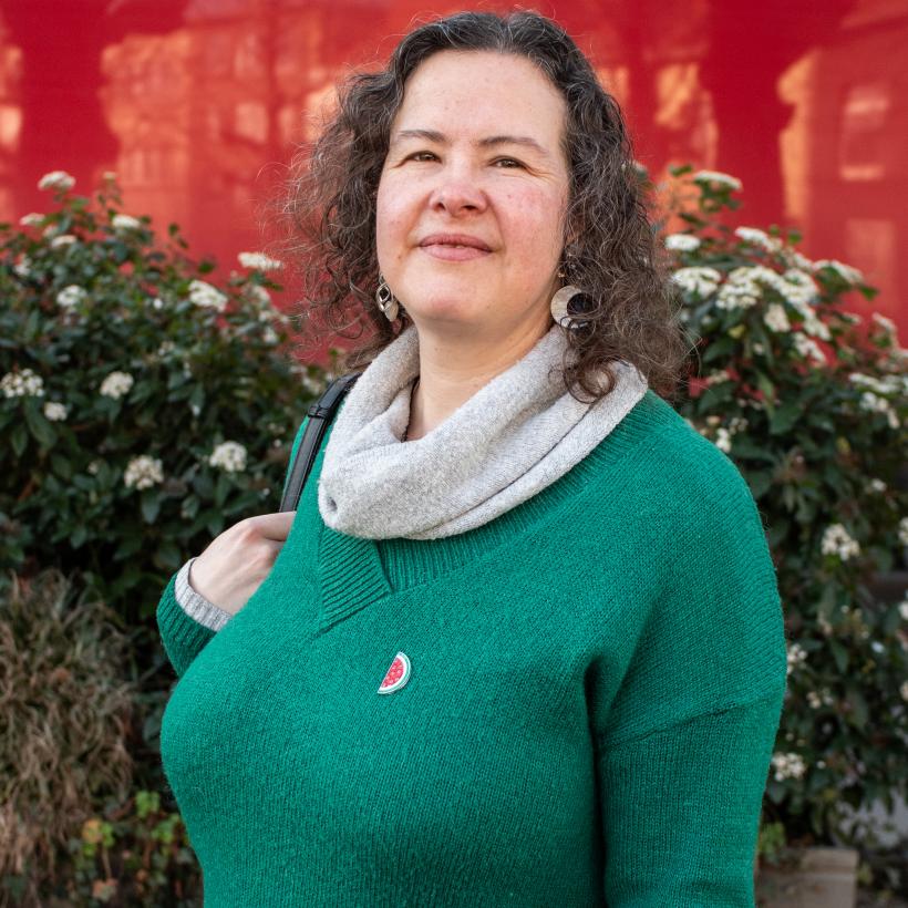 Femme aux cheveux gris portant une broche palestine.