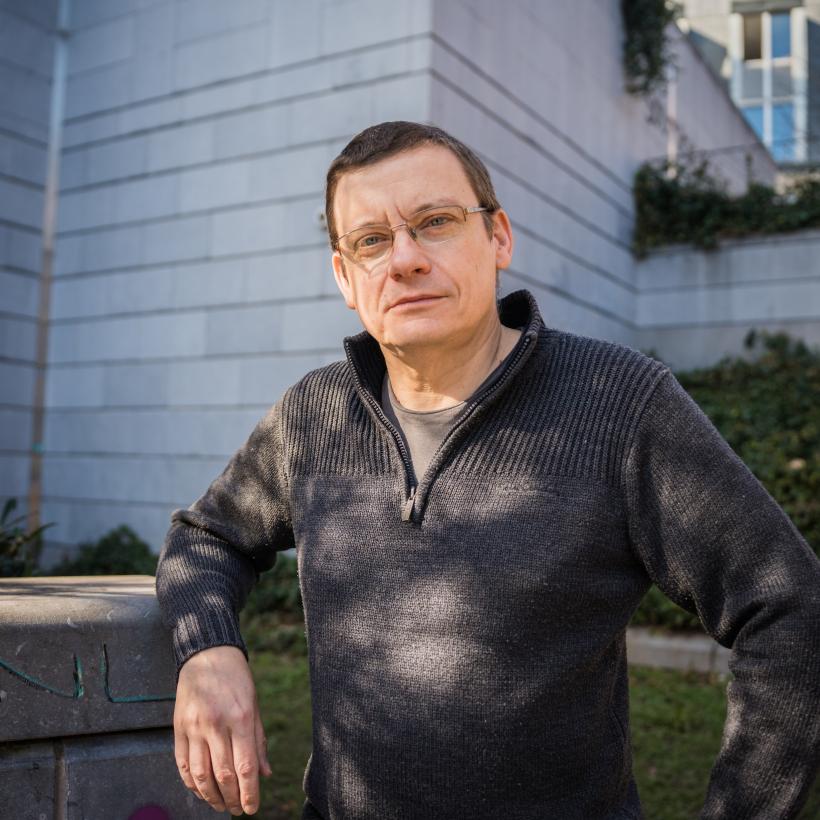 un homme avec des lunettes regarde la caméra