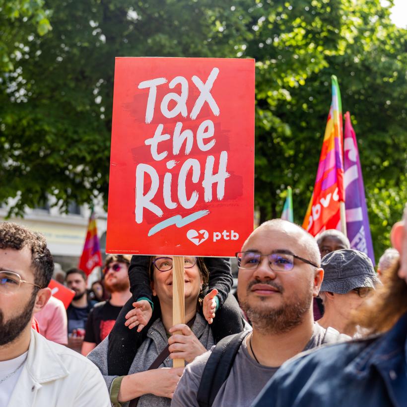 Une pancarte "Tax The Rich" au milieu d'une manifestation.