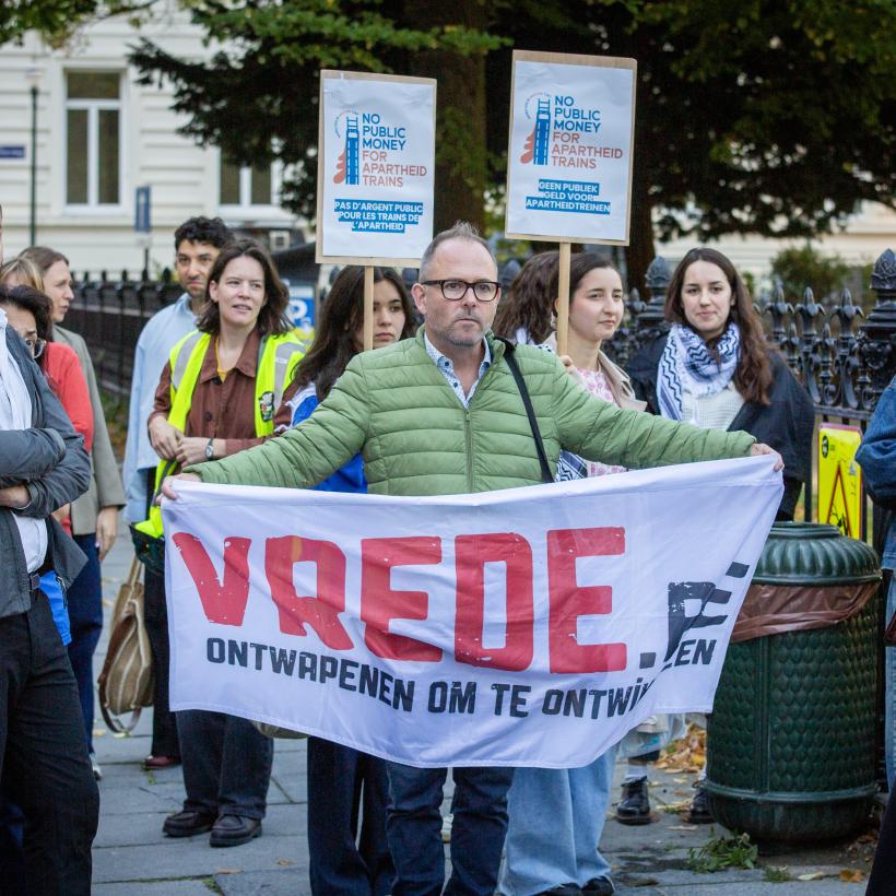 Quelqu'un tient une banderole avec écrit "Vrede" : "paix".