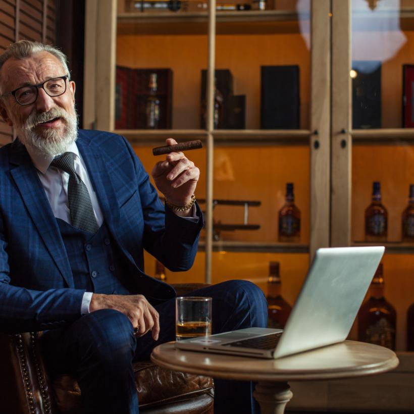 Un homme riche avec un cigare dans un bureau majestueux, un ordinateur portable ouvert sur la table.