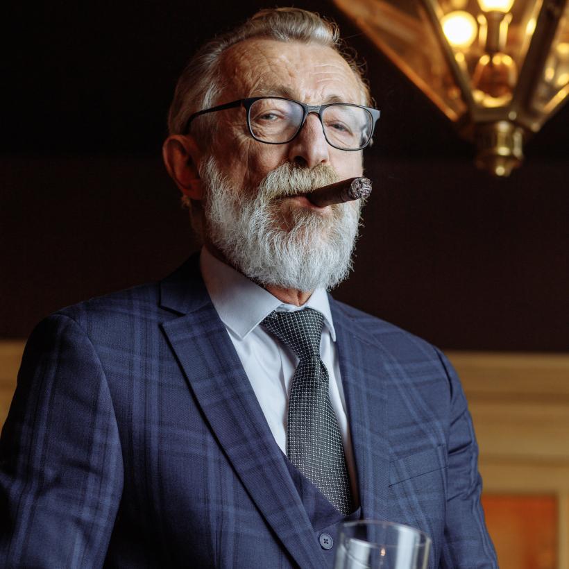 Un millionnaire avec un cigare regarde de haut la caméra