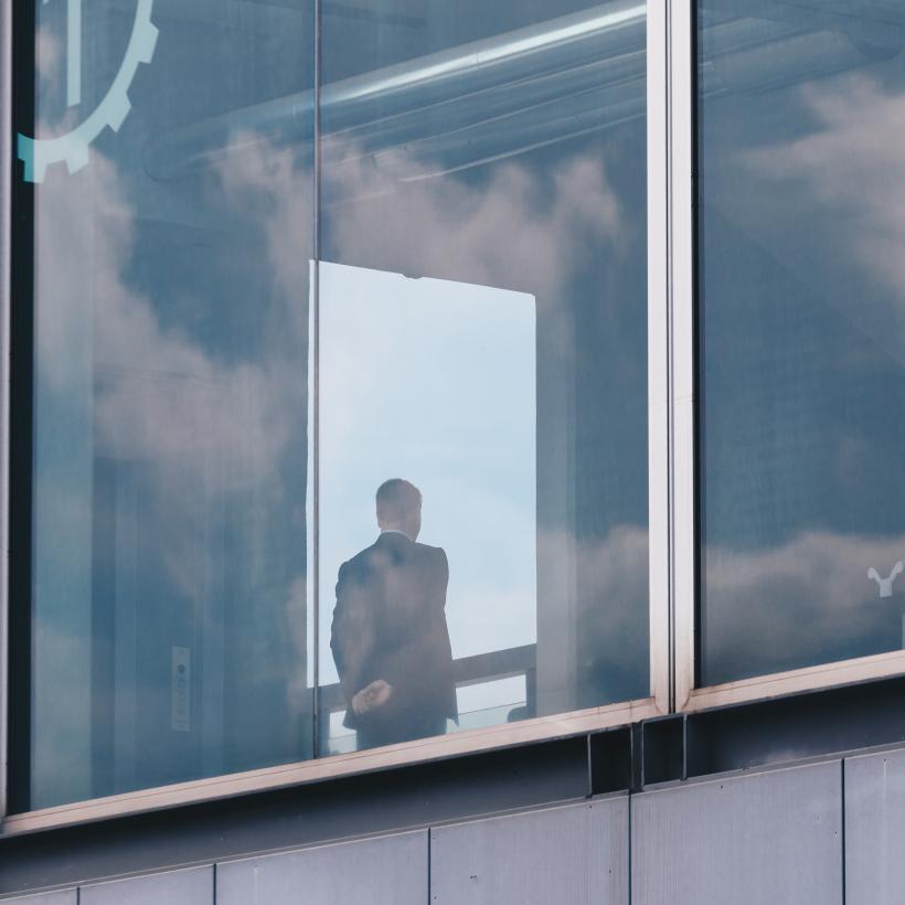 Een zakenman van achteren gezien achter het raam van een gebouw.