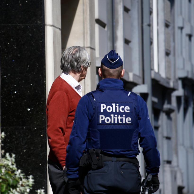 Un policier belge parle à un homme devant l'entrée d'une maison.