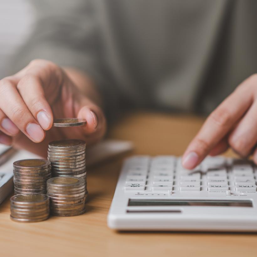 Un homme calcule les impôts avec des pièces et une calculatrice