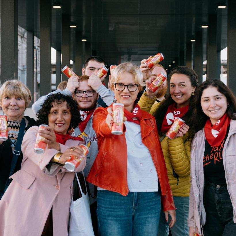 Sofie Merckx et des membres posent avec des canettes "Taxe des millionnaires - l'authentique" lors d'une action.