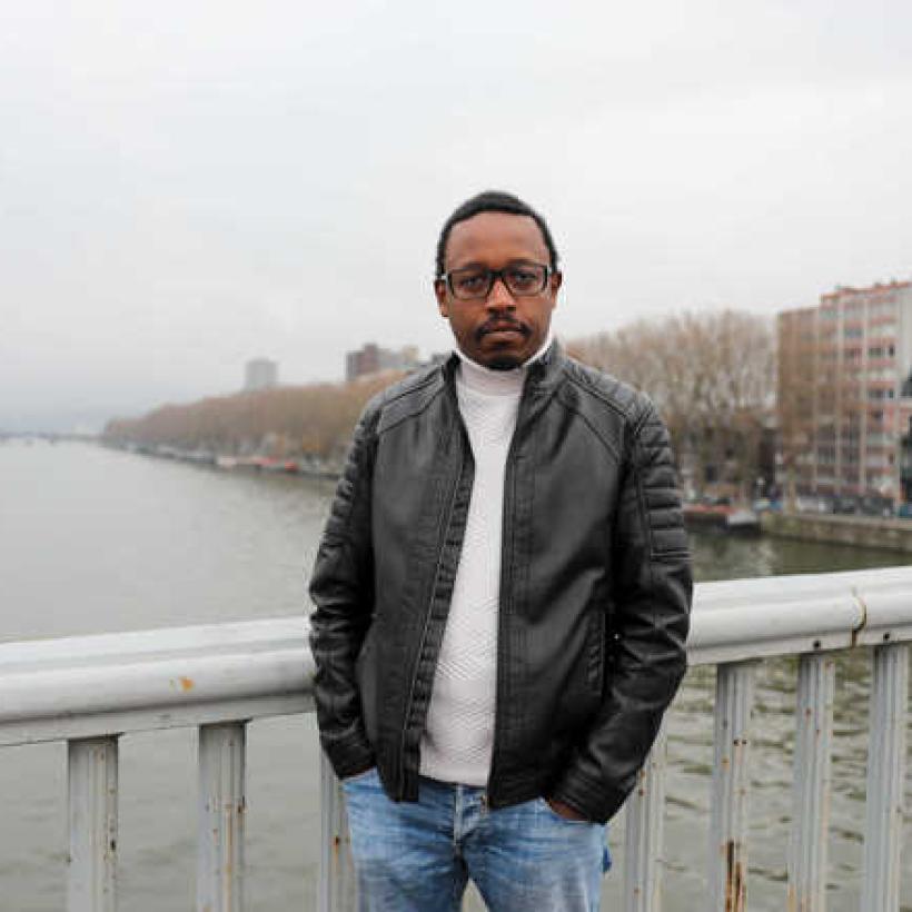 Germain Mugemangango debout sur le pont au-dessus de la Meuse.