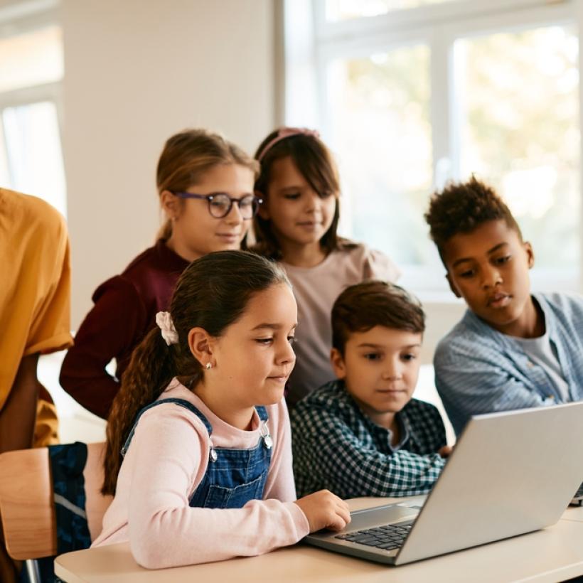 Des enfants regardent ensemble l'écran d'un ordinateur dans une salle de classe.