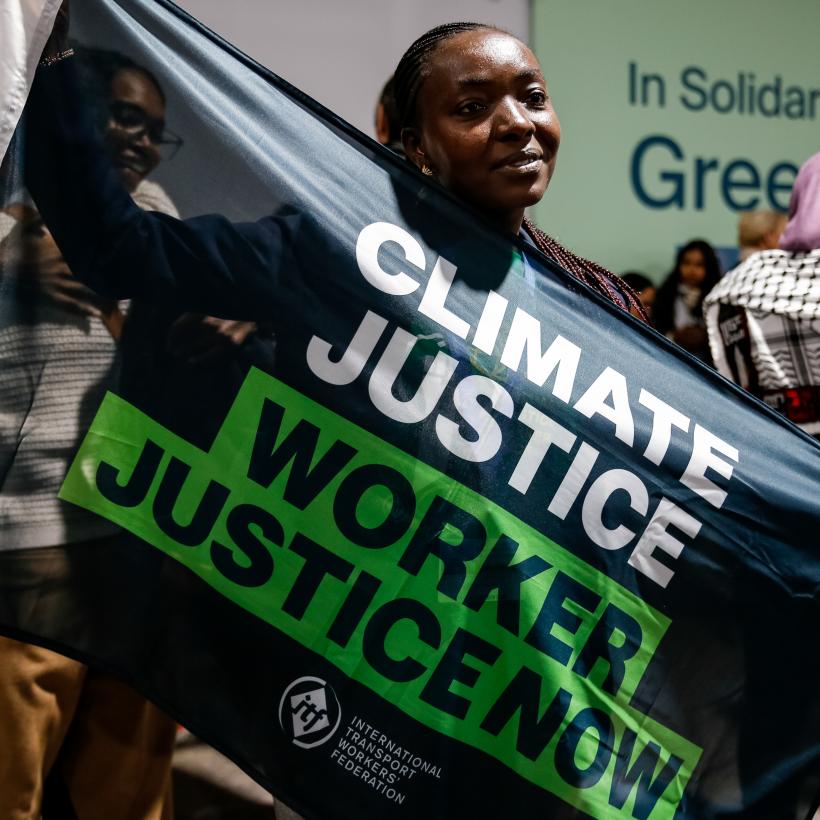 Une syndicaliste tient une banderole pour réclamer la justice climatique et pour les travailleurs lors de la COP29.