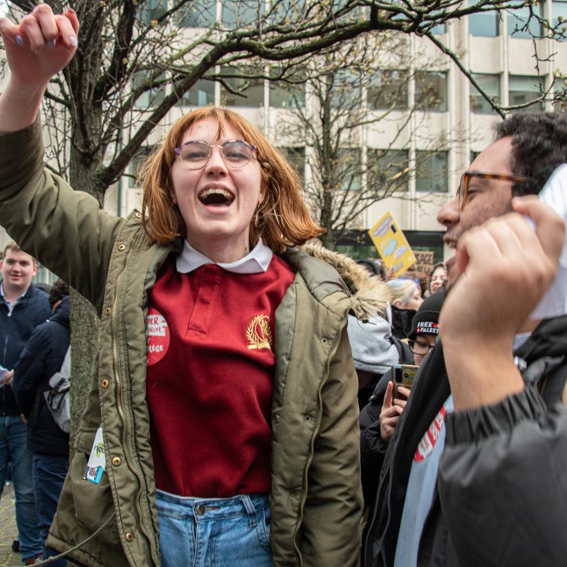 Une jeune femme lève le poing dans une manifestation d'étudiants.