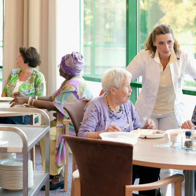 Des personnes sont à table dans une maison de repos