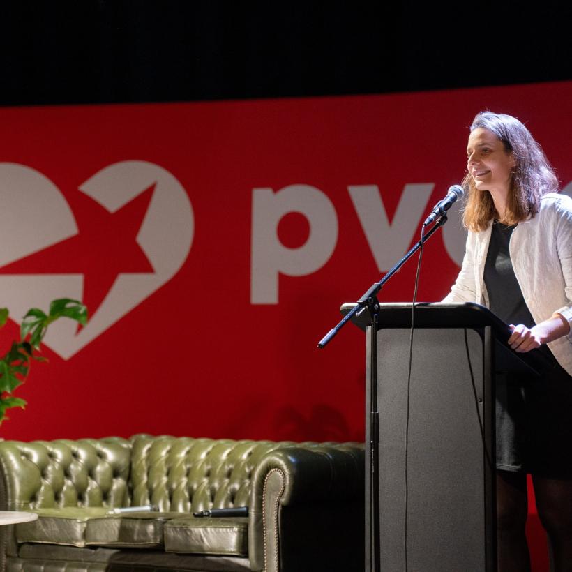 Anne Delespaul staat op een podium en spreekt in de microfoon