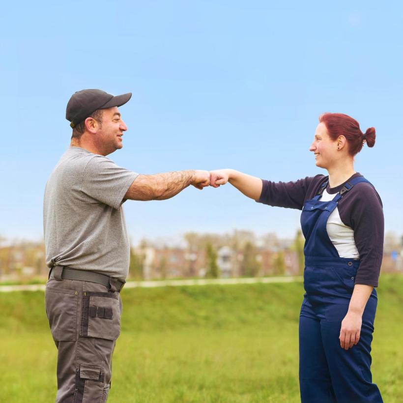 Photo d'un homme et une femme en tenue de travail qui se saluent avec le poing.