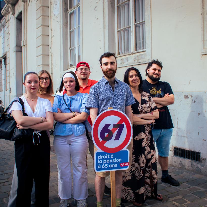 Un groupe de gens tiennent une pancarte avec un 67 barré