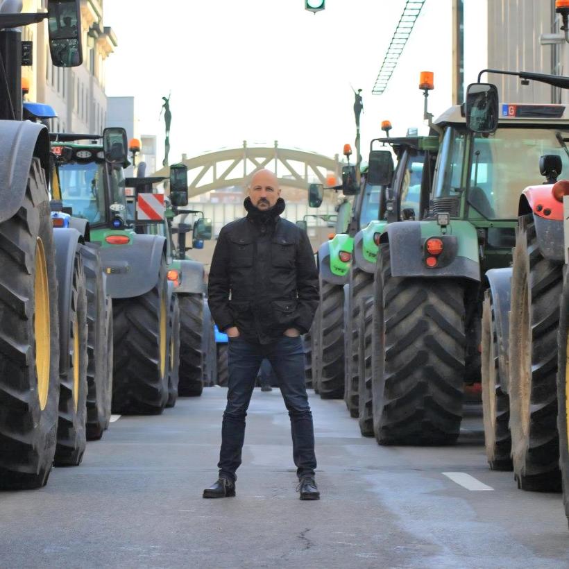 Marc Botenga se tient entre deux rangées de tracteurs