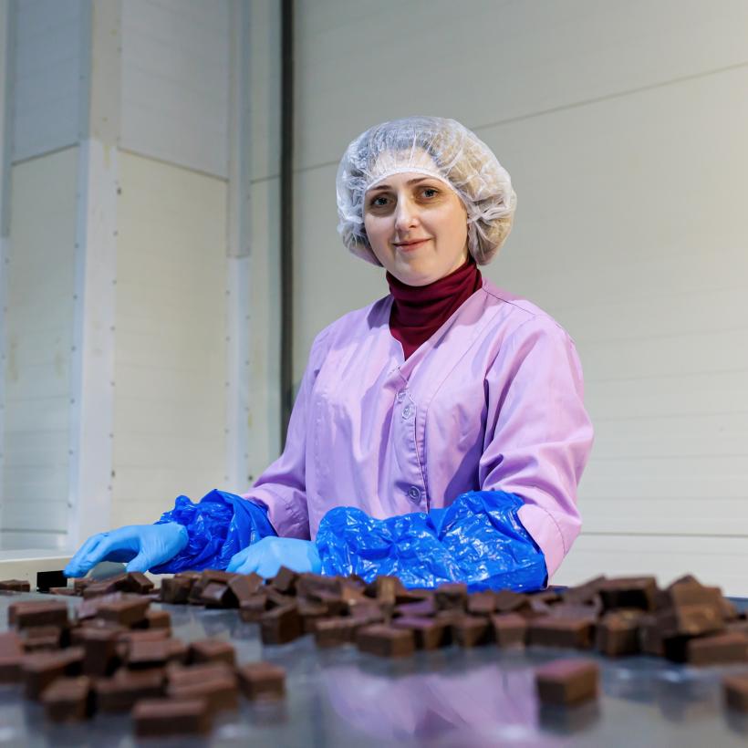 Une travailleuse avec un filet dans les cheveux travaille sur une production de nourriture en chocolat