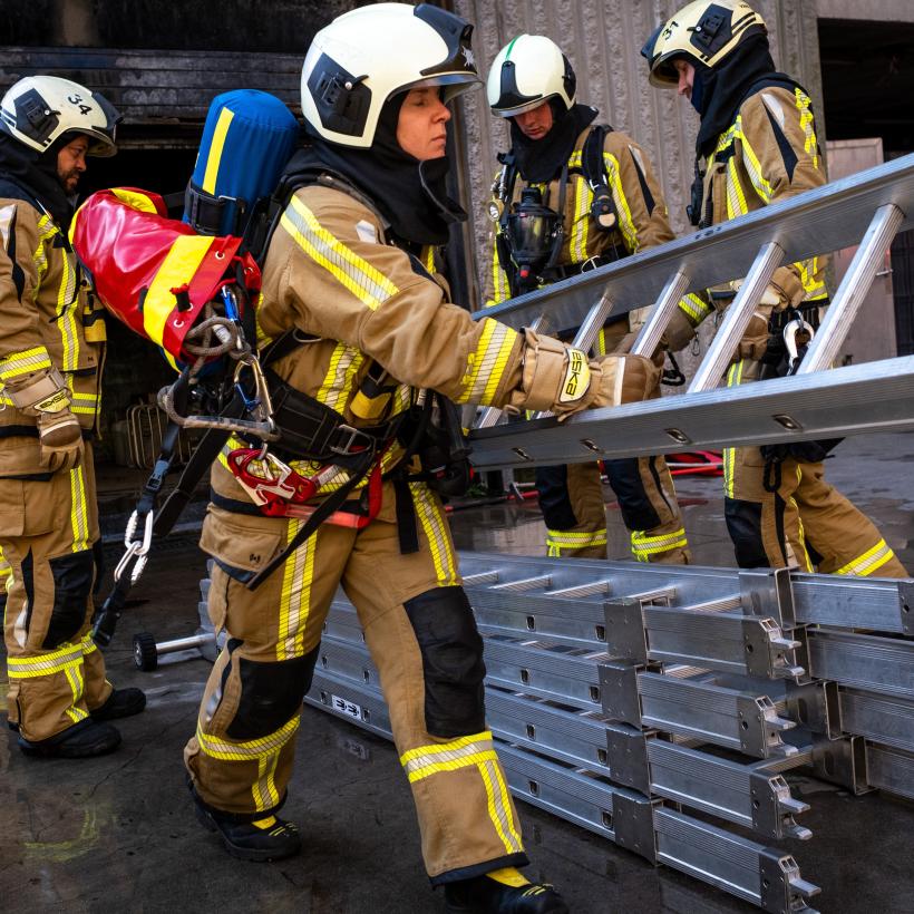 Un groupe de pompiers portent des échelles