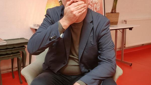 Raoul Hedebouw est assis et met une main sur sa bouche.